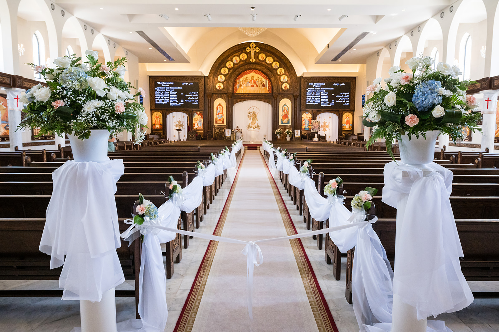 Church aisle with floral arrangements and pew draping