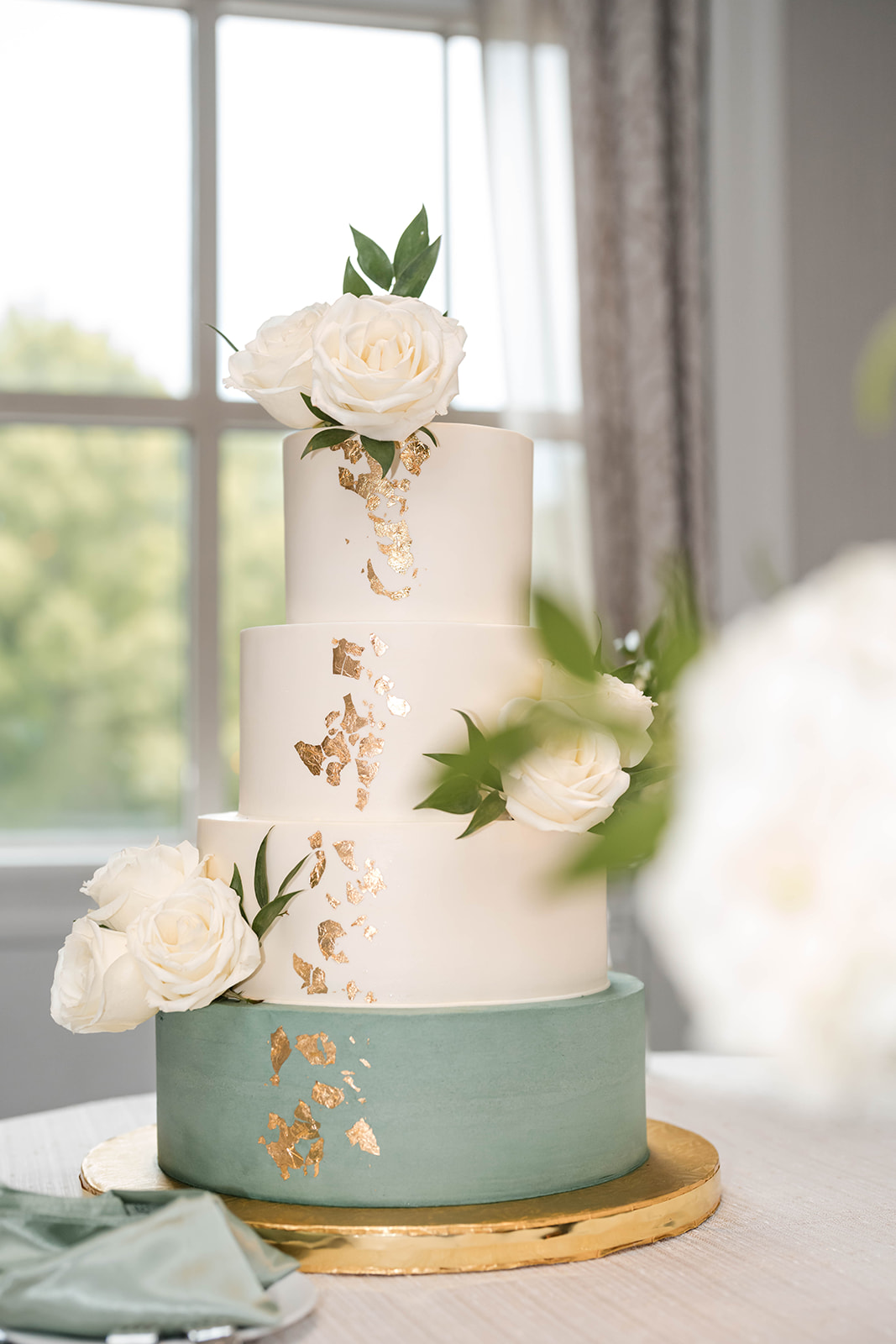 Four tier cake sage and gold leaf with white roses
