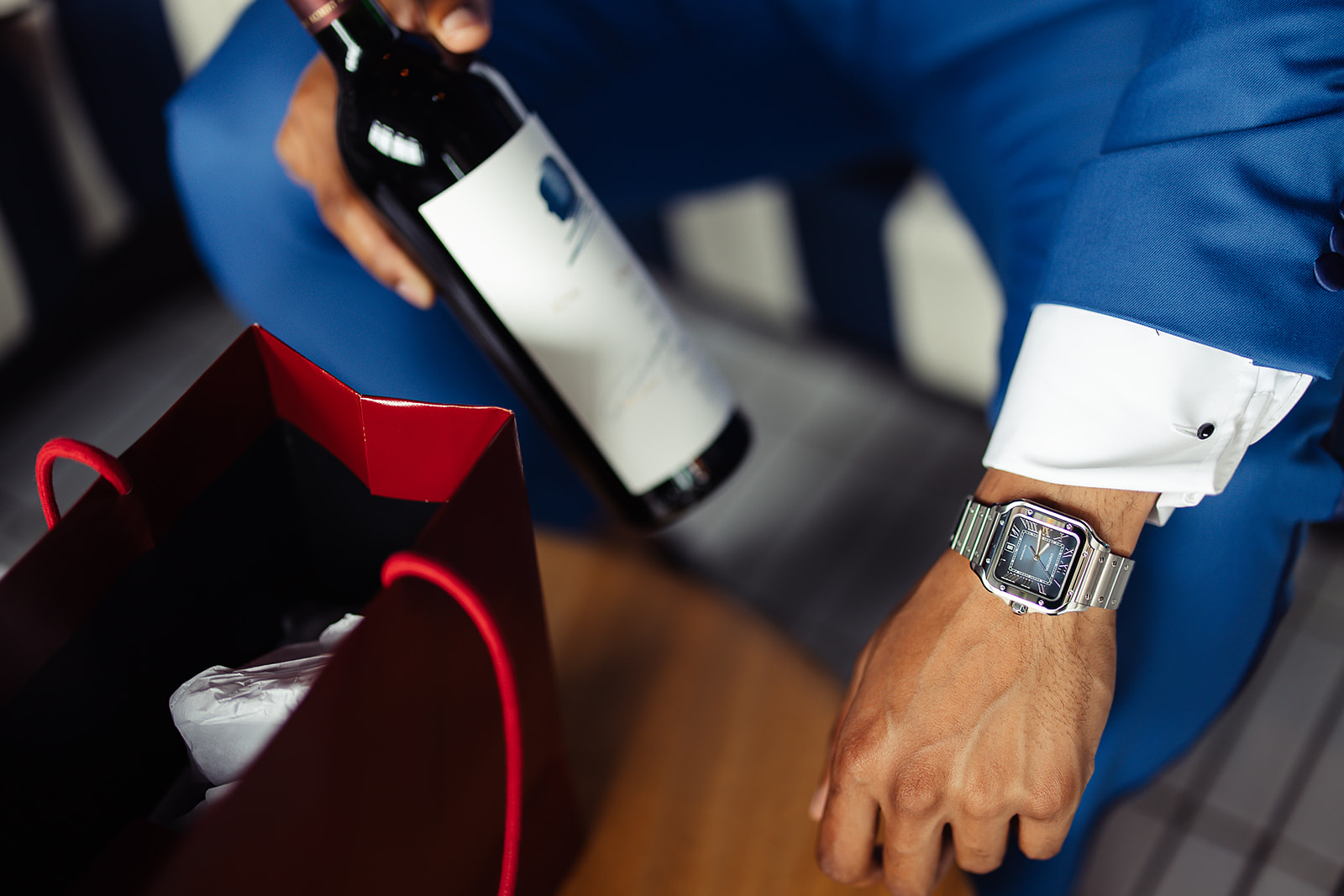 Groom watch and wine bottle blue suit closeup