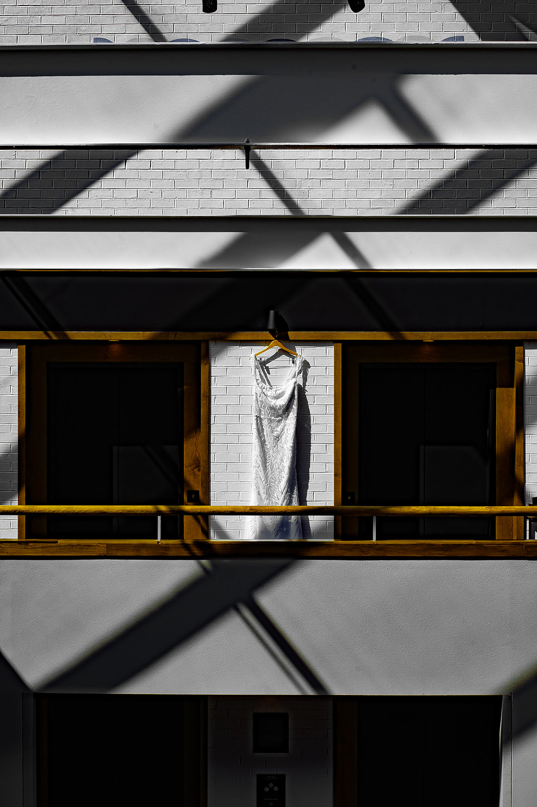 Wedding dress hanging on balcony with architectural shadows