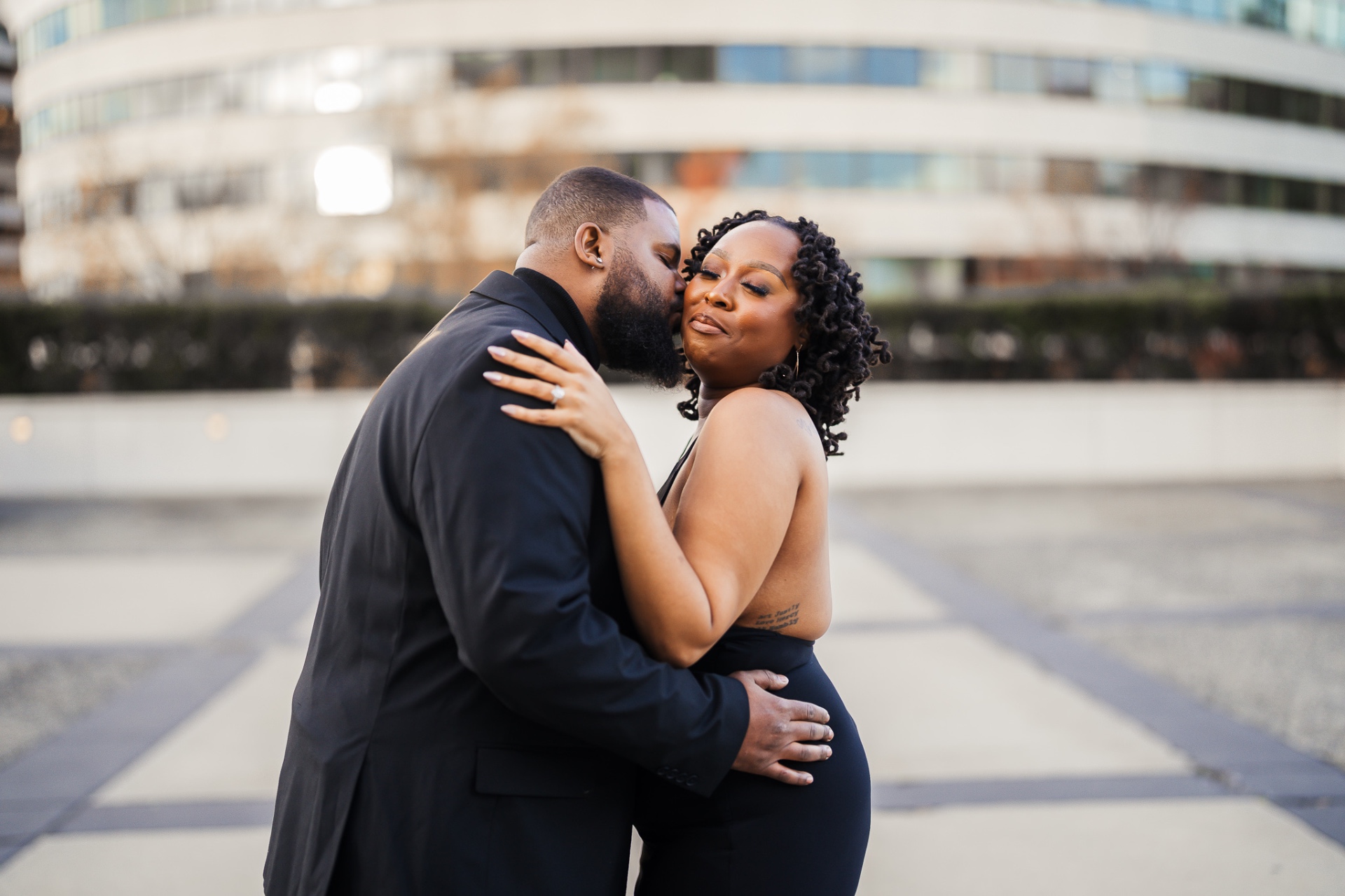 Couple cheek kiss at urban plaza candid