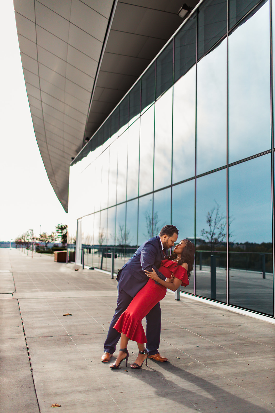 Couple dip kiss modern glass building red dress blue suit