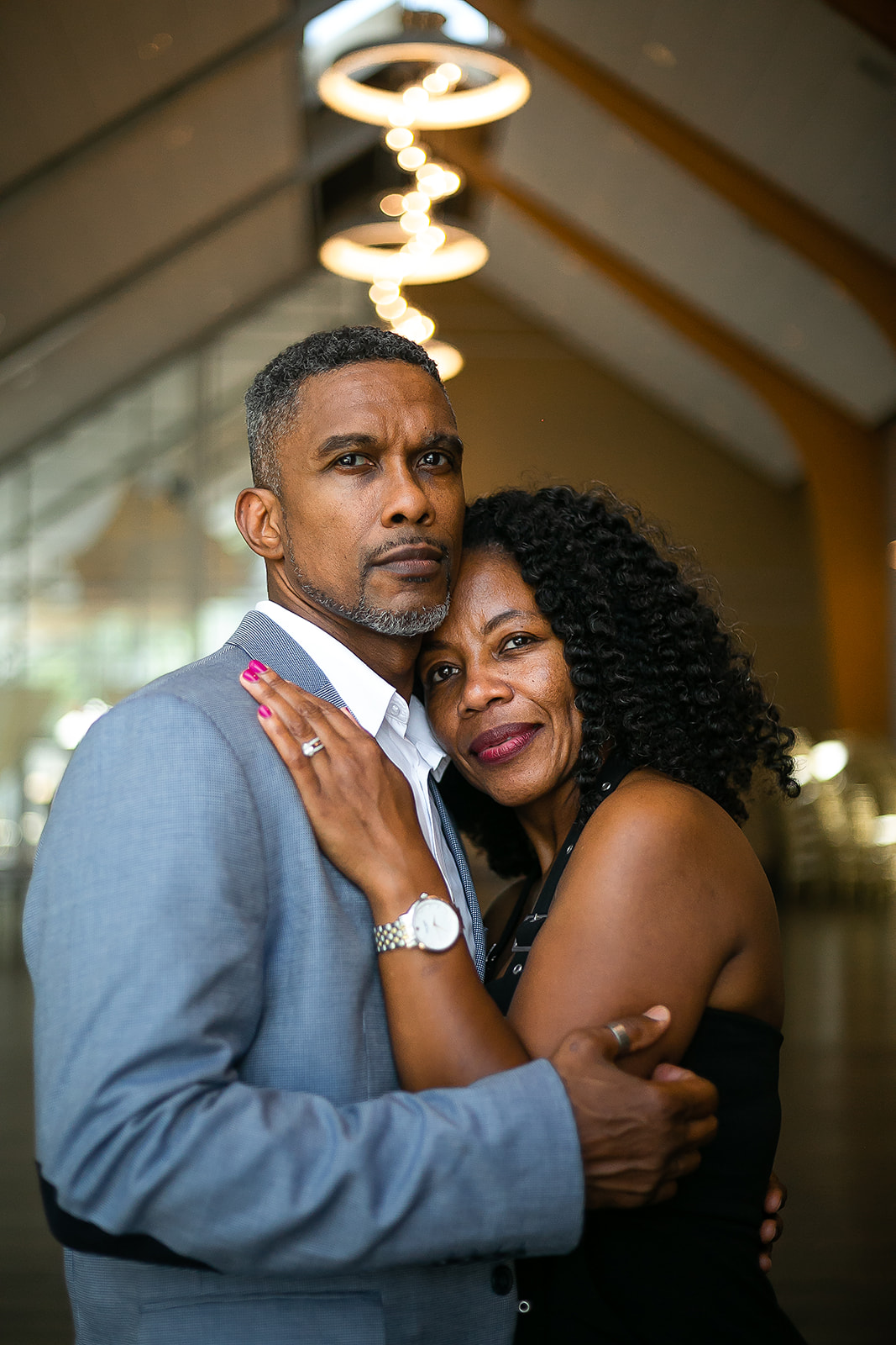 Couple embrace in chandelier lobby with warm light intimate portrait