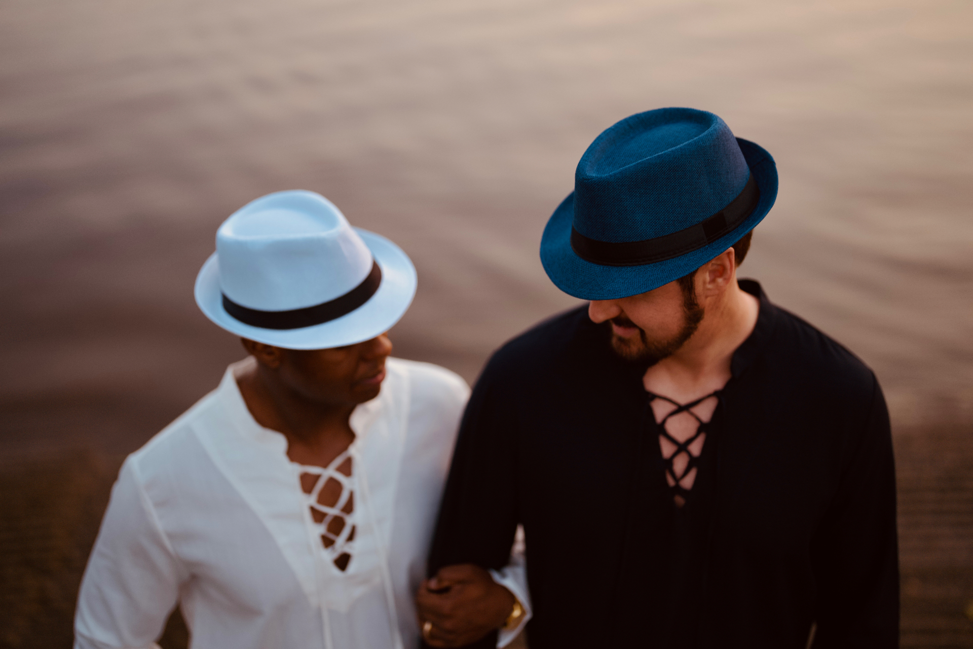 Couple in matching fedora hats sunset beach editorial