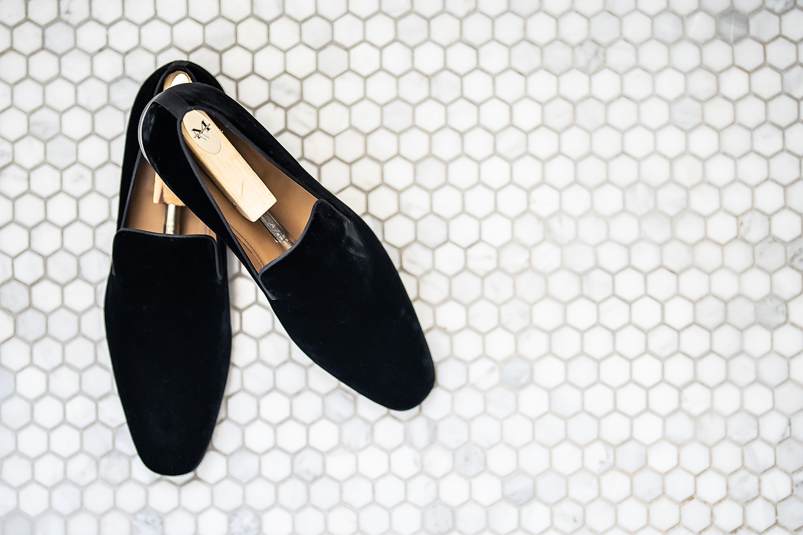 Black velvet loafers on marble hexagonal tile floor
