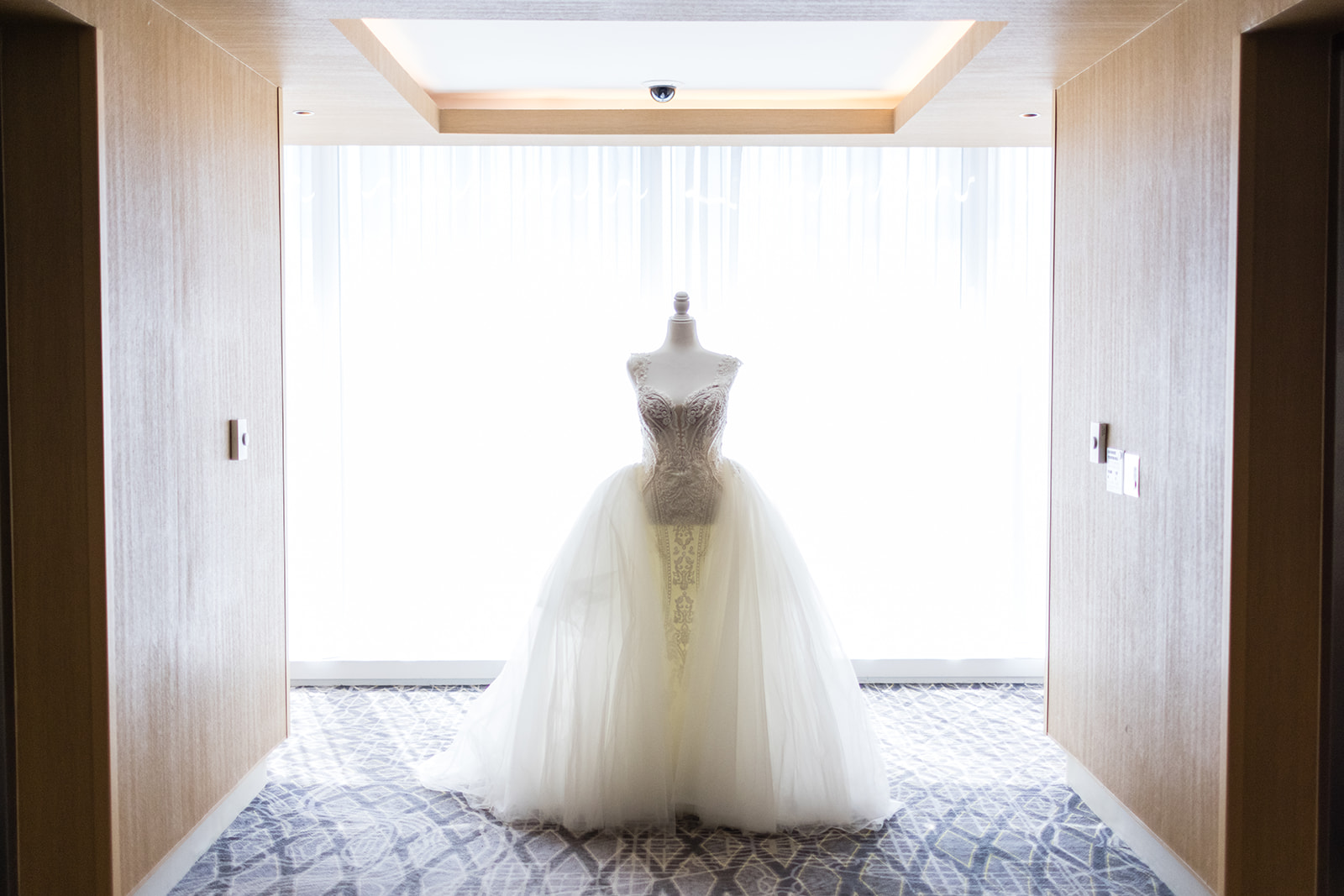 Bridal tulle ball gown on mannequin in luxury hotel hallway backlit