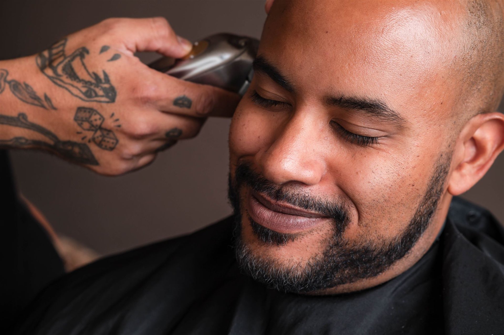 Groom getting haircut from barber with tattooed hands closeup