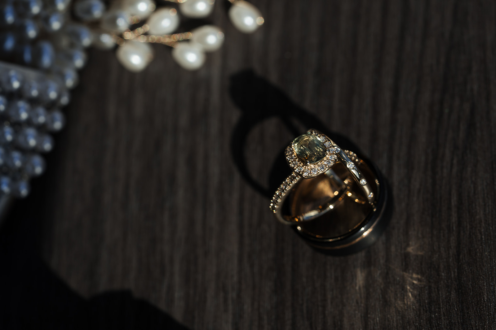 Cushion halo ring with pearl hairpiece on dark wood moody