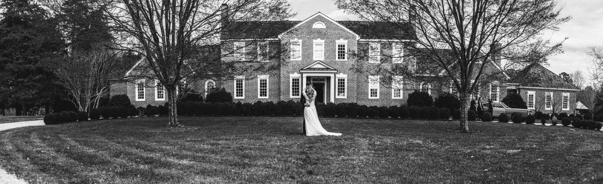 Bride at colonial mansion lawn panoramic black and white