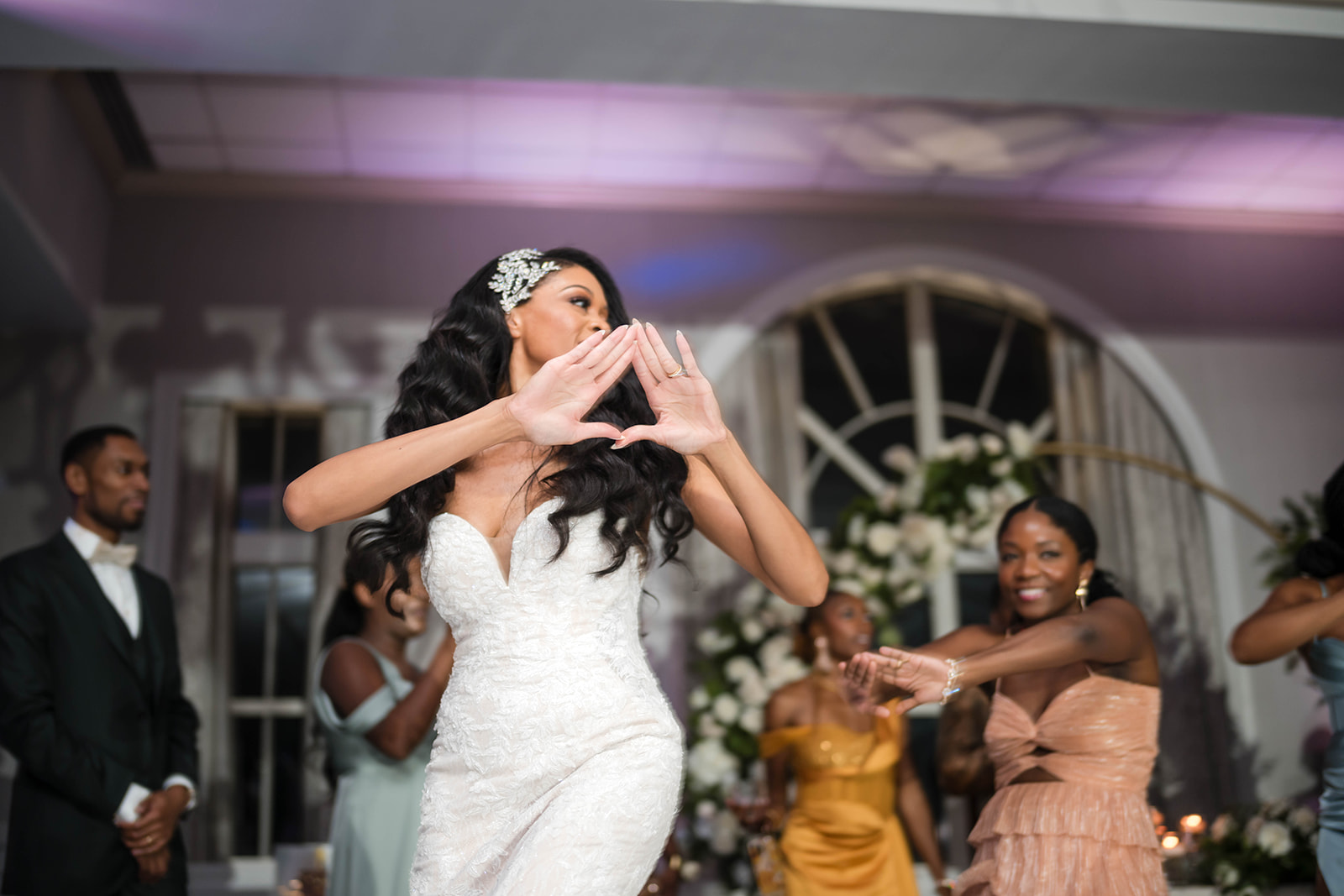 Bride throwing delta hand sign on reception dance floor party