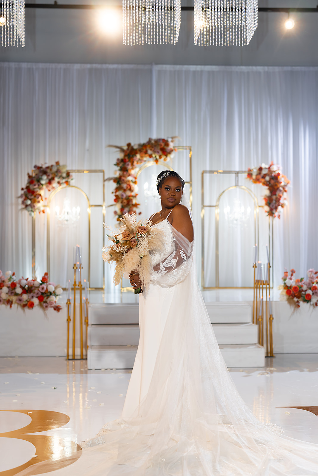 Bride at gold arch ceremony backdrop with pampas bouquet