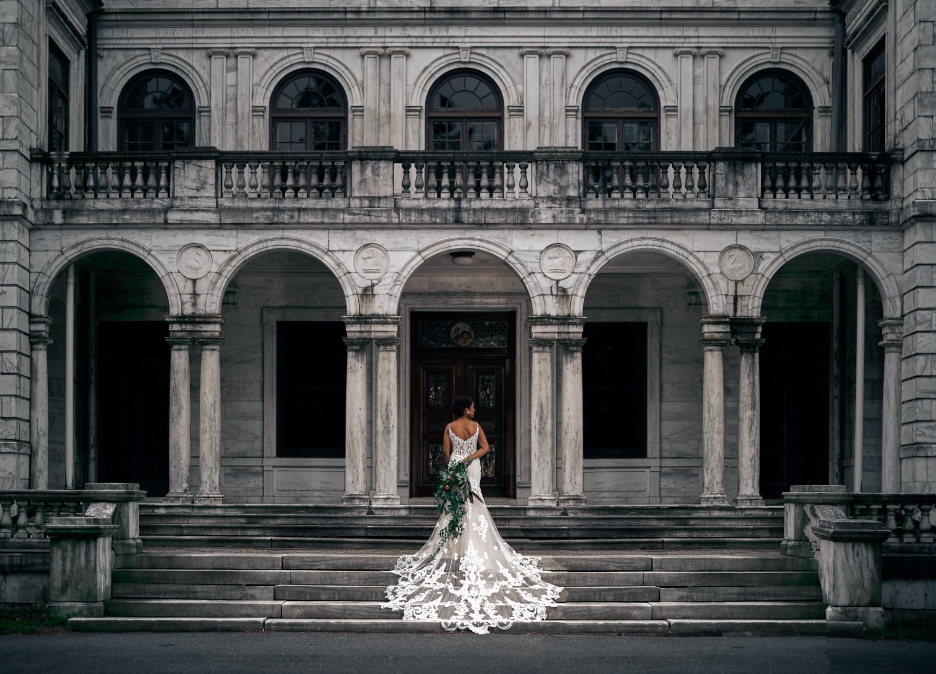 Bride on grand mansion steps with cathedral train and bouquet