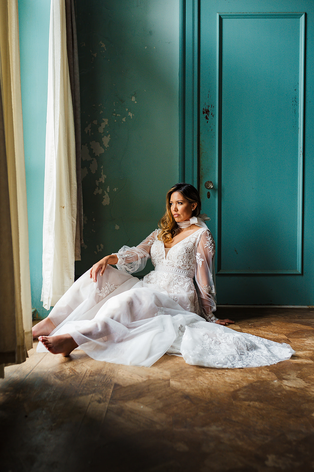 Bride seated in teal room lace gown window light editorial