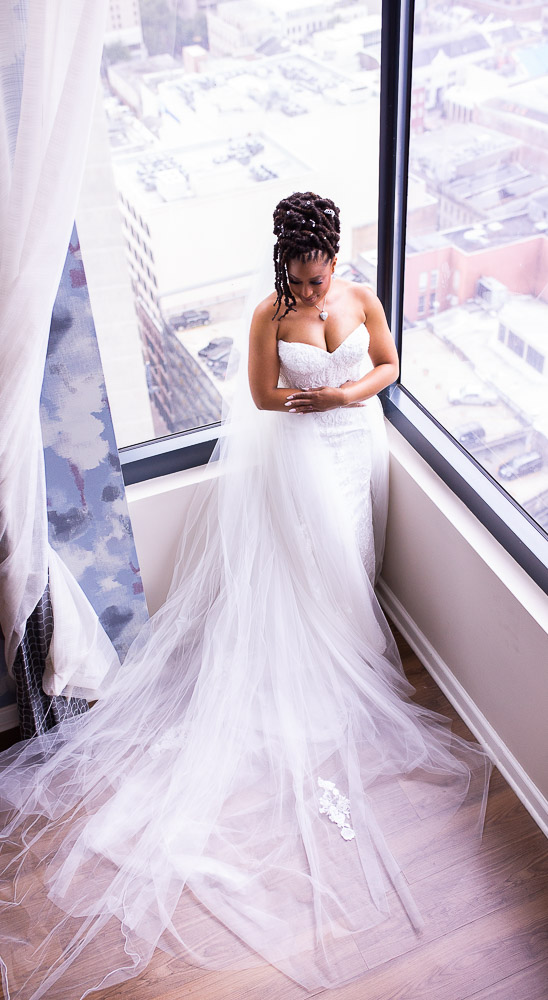Bride in tulle gown by window overlooking cityscape