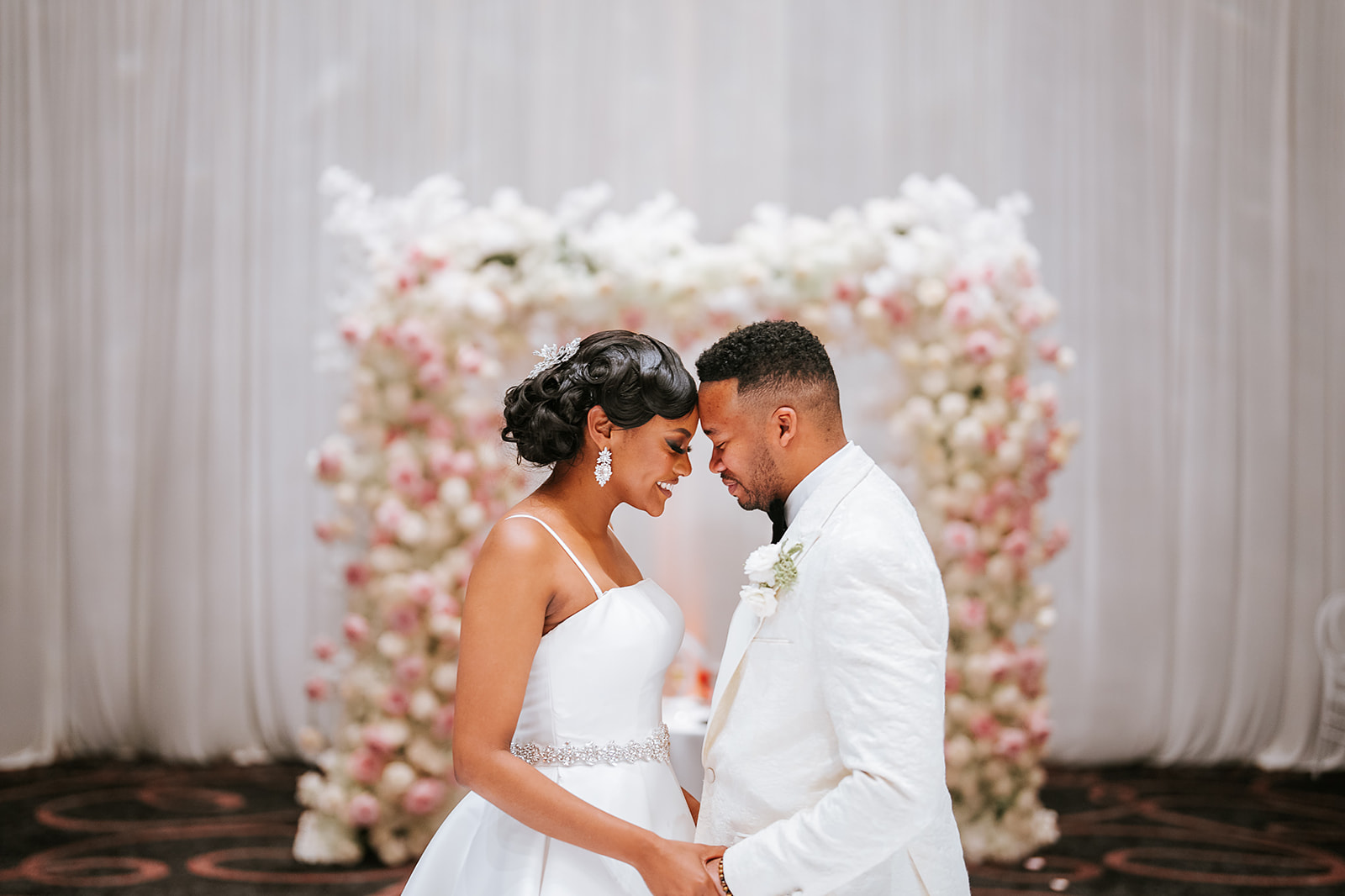 Couple under floral heart arch