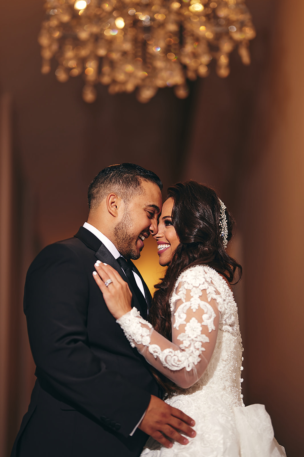Couple intimate portrait under chandelier with lace sleeve detail