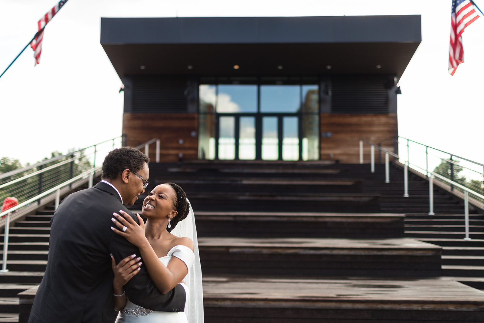 Couple laughing at modern venue steps with American flags