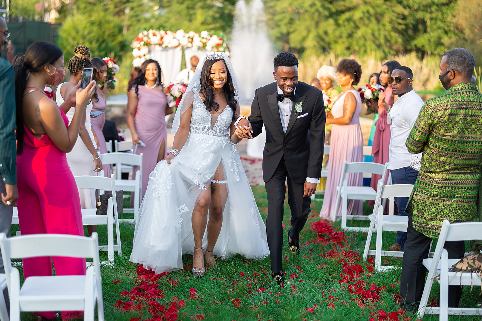 Couple recessional down aisle with rose petals outdoor ceremony joyful