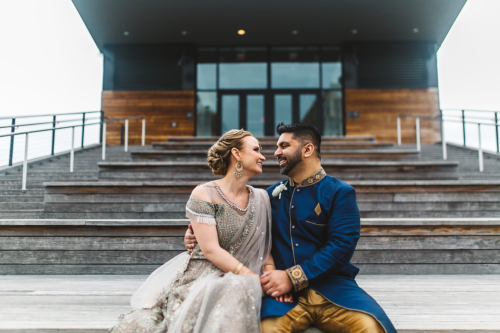 Couple in South Asian fusion attire modern venue steps portrait