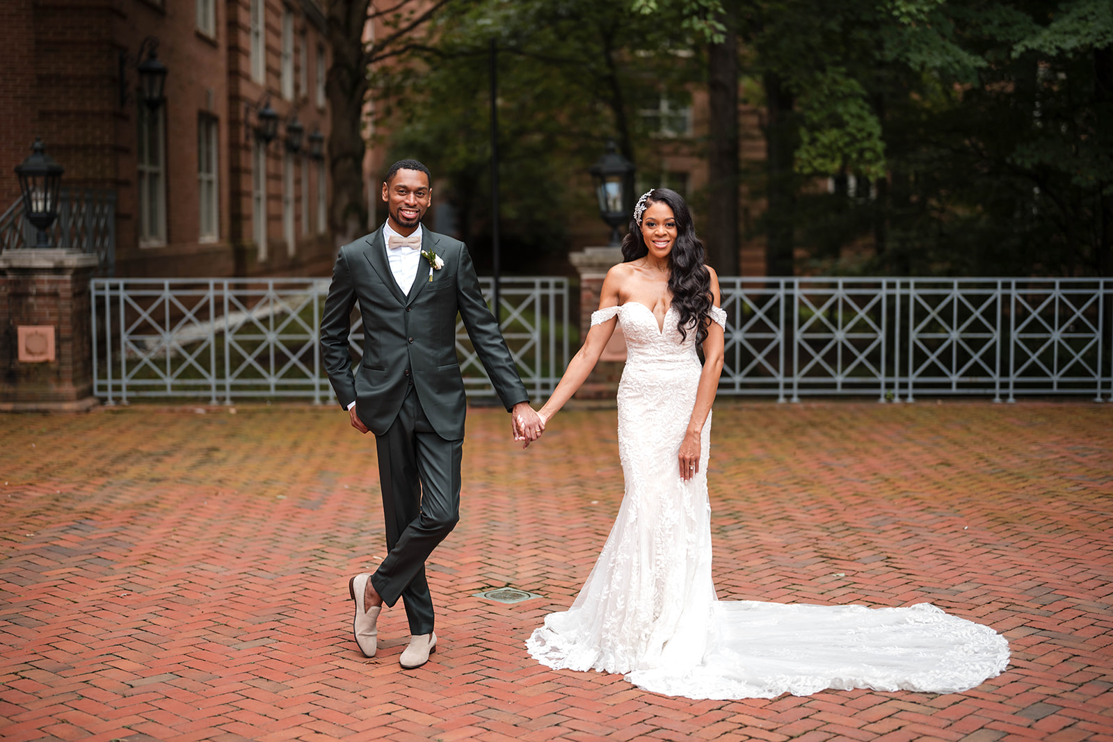 Couple walking hand in hand brick courtyard mermaid gown portrait