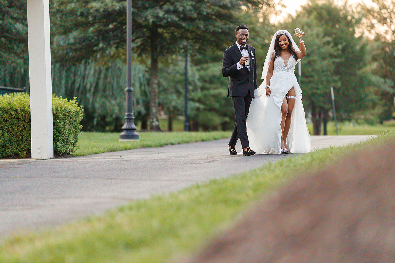 Couple walking with champagne celebrating in park at golden hour