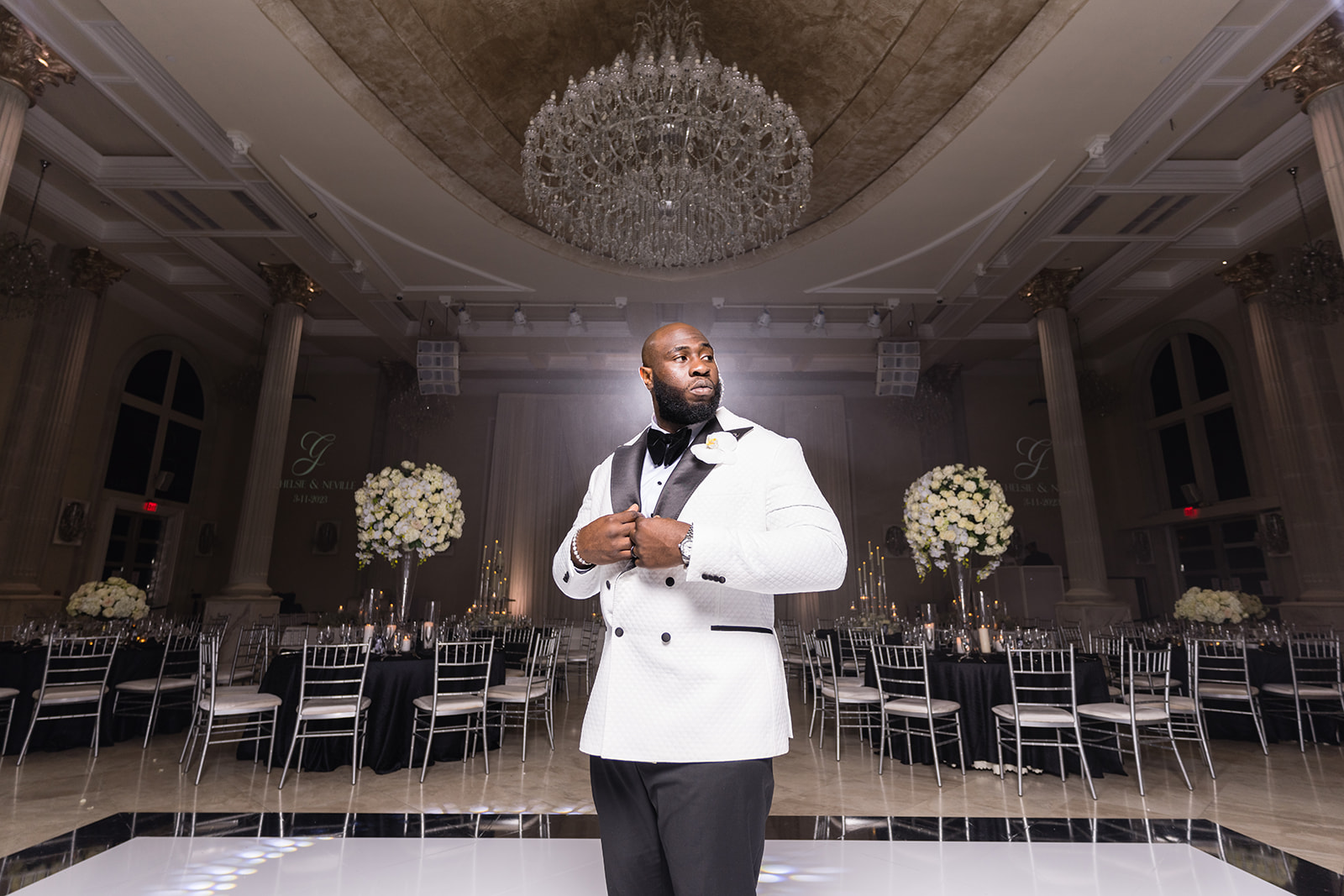 Groom in white tuxedo ballroom chandelier portrait