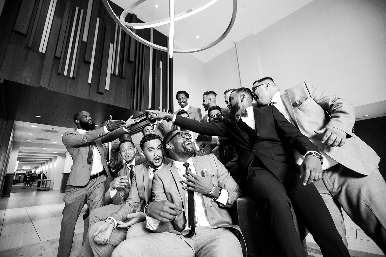Groomsmen laughing dog pile black and white modern venue candid
