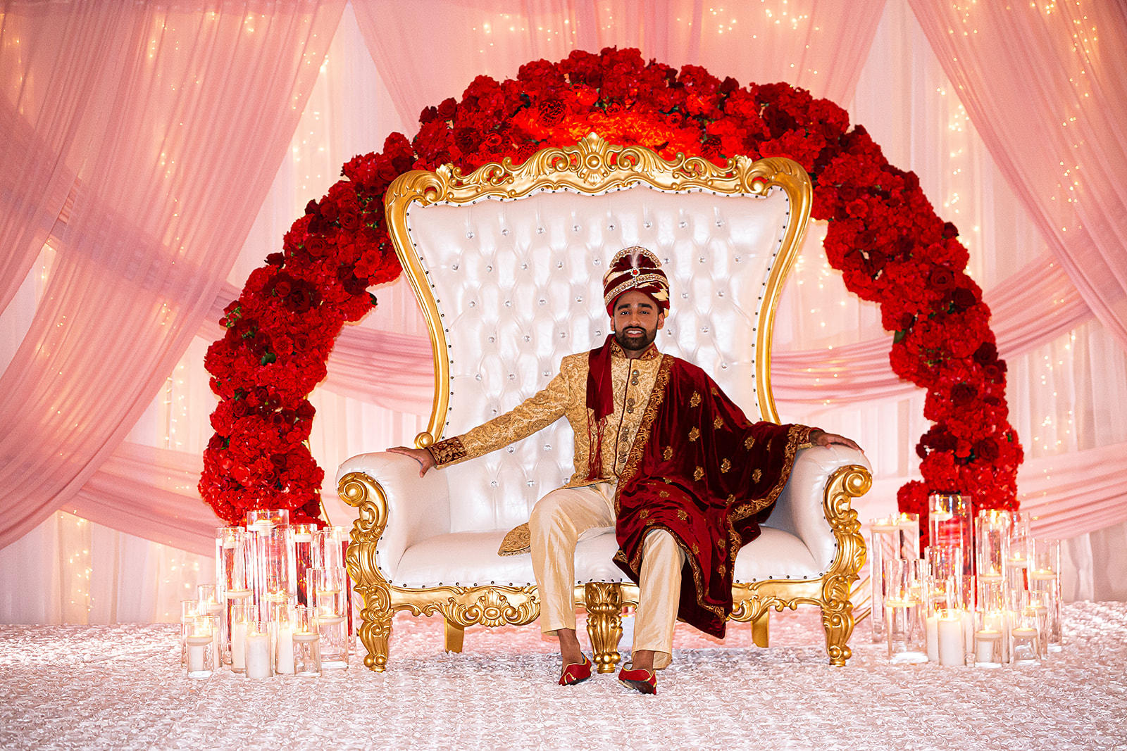 South Asian groom on throne with red roses and candles
